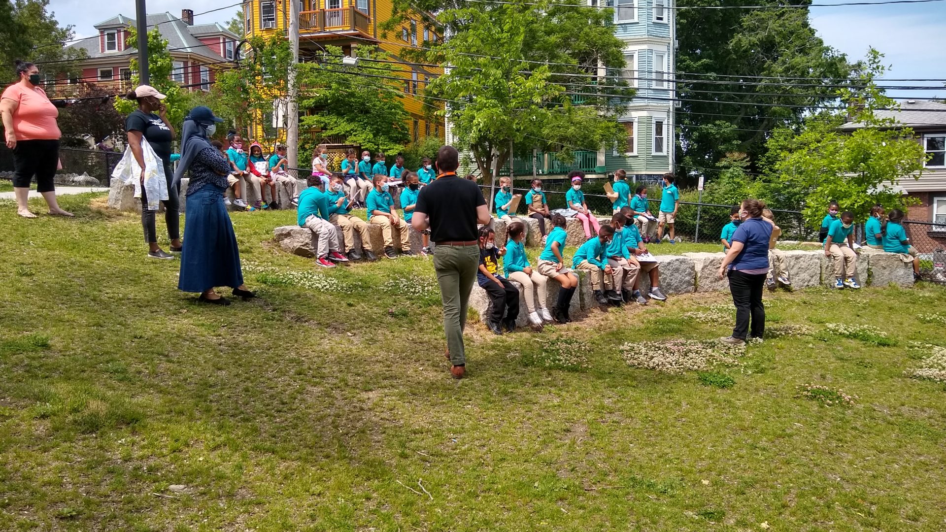 Teachers stand next to an amphitheatre filled with a group of students during a walking field trip.